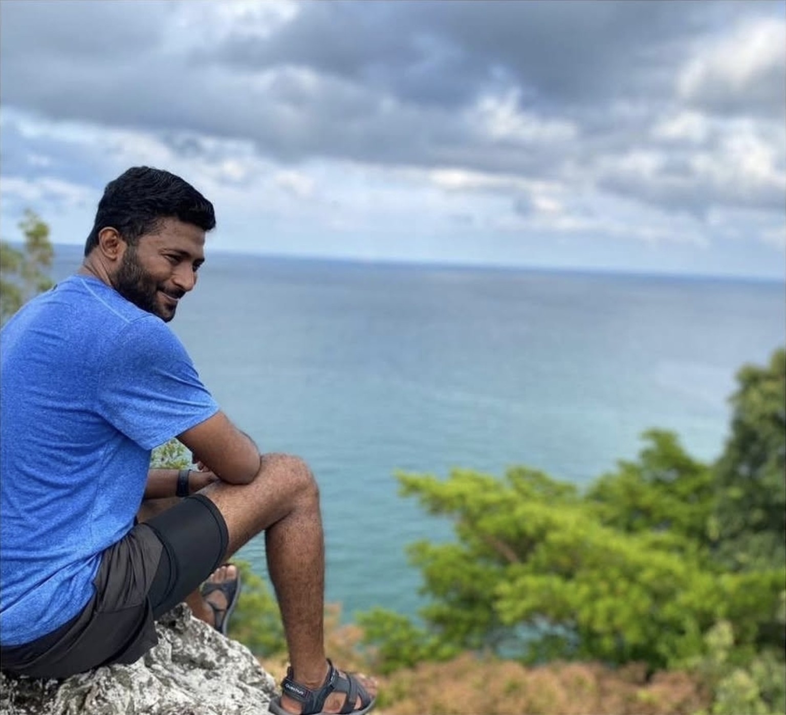 Thana sitting at the Bukit Batu Putih viewpoint overlooking the sea