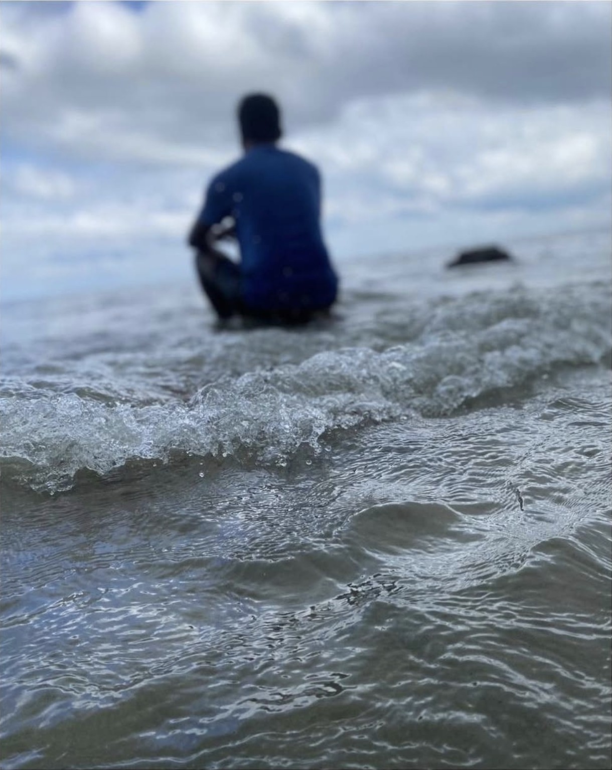 Thana sitting in the sea with waves in the foreground