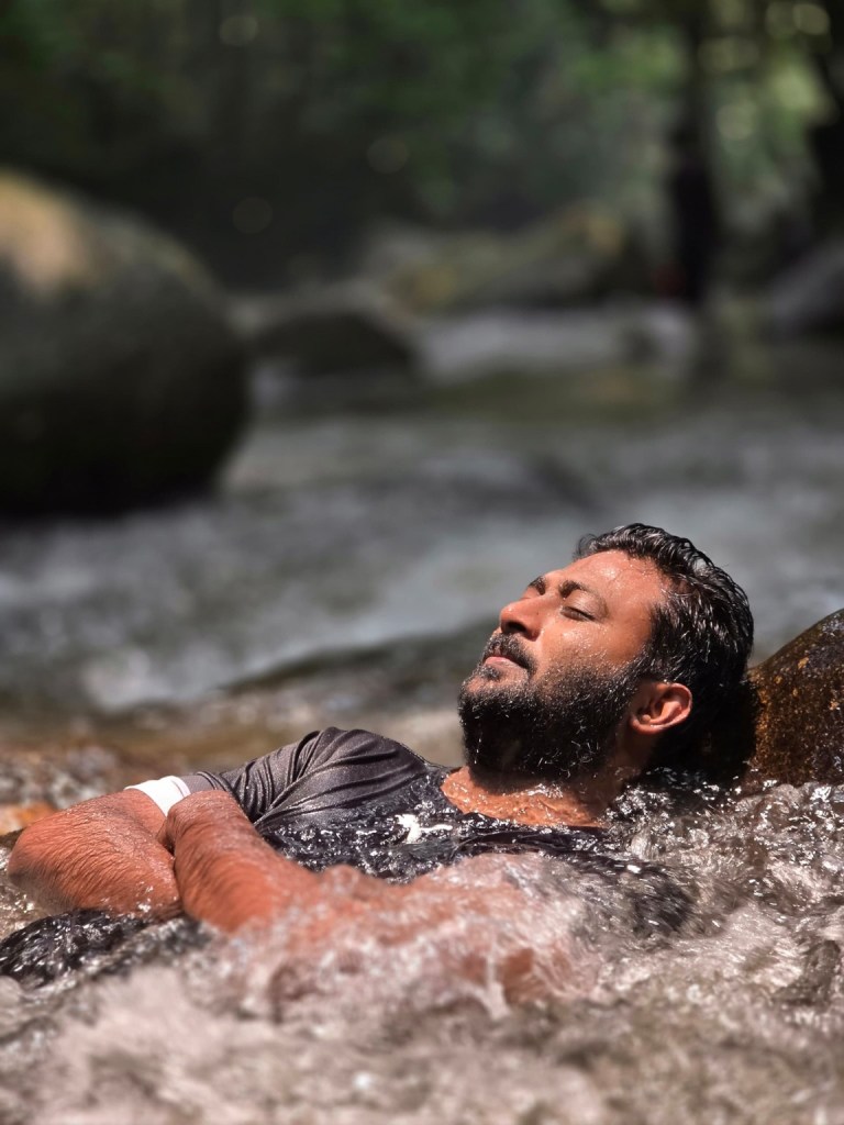 Thana relaxing with eyes closed under the waterfall at Sungai Tua