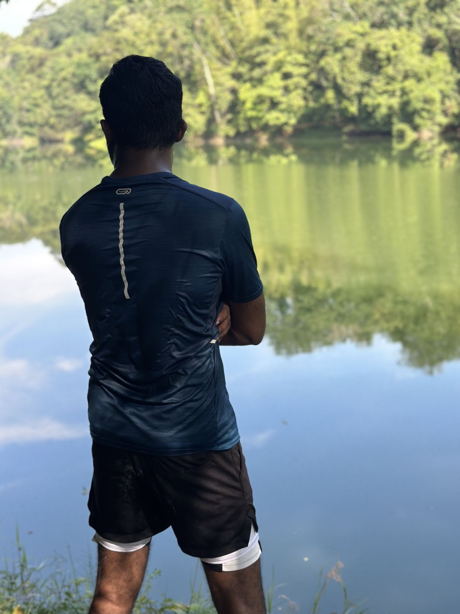 Thana standing by a lake with trees reflected in the water.