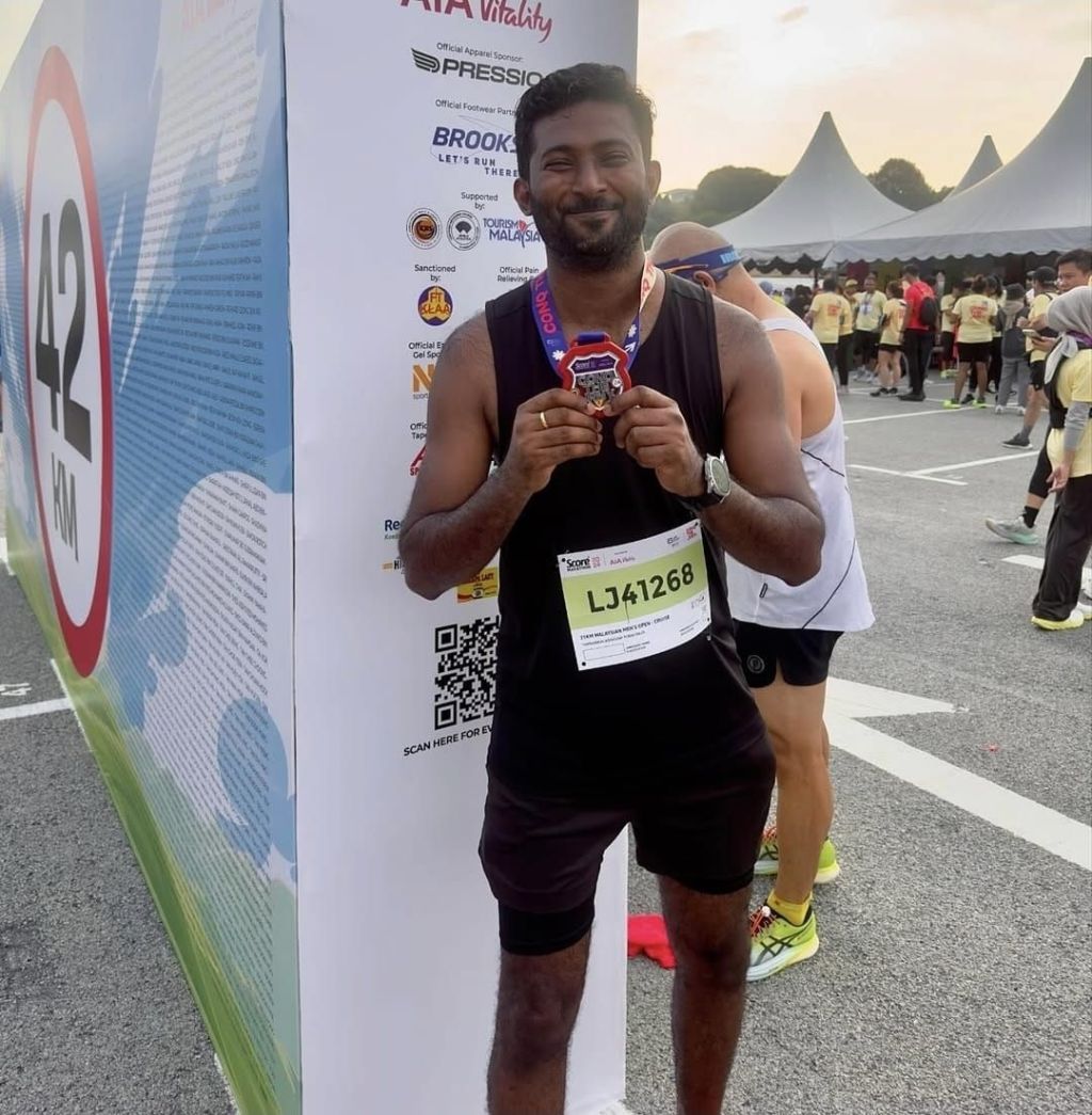 Thana holding his medal after completing a 21.1 km half marathon