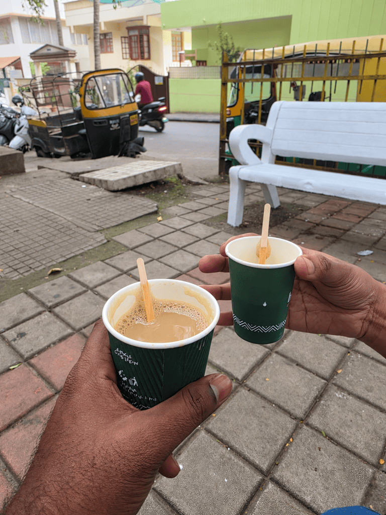 Two green coffee cups held beside a Bangalore street