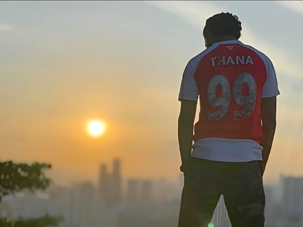 Thana in a red jersey looking toward the sunrise over the city.