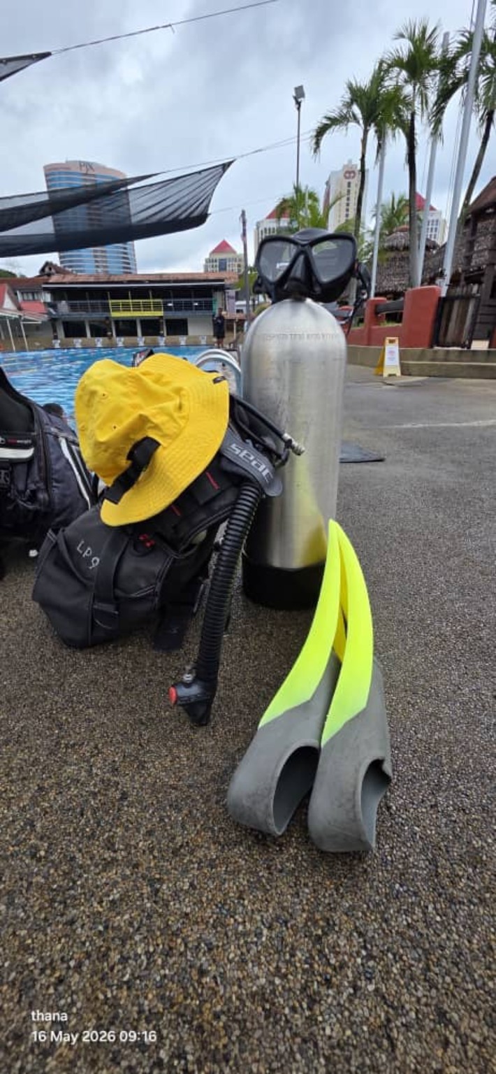 Scuba tank, mask and fins beside the swimming pool.