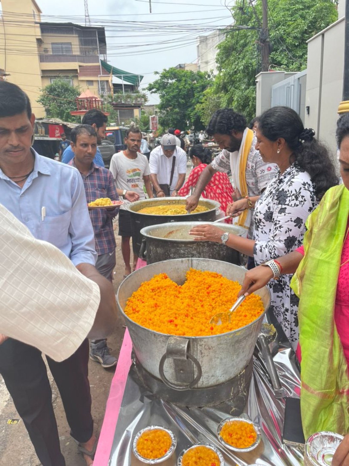 Family serving food from large pots outside the Sai Baba temple in Kashi