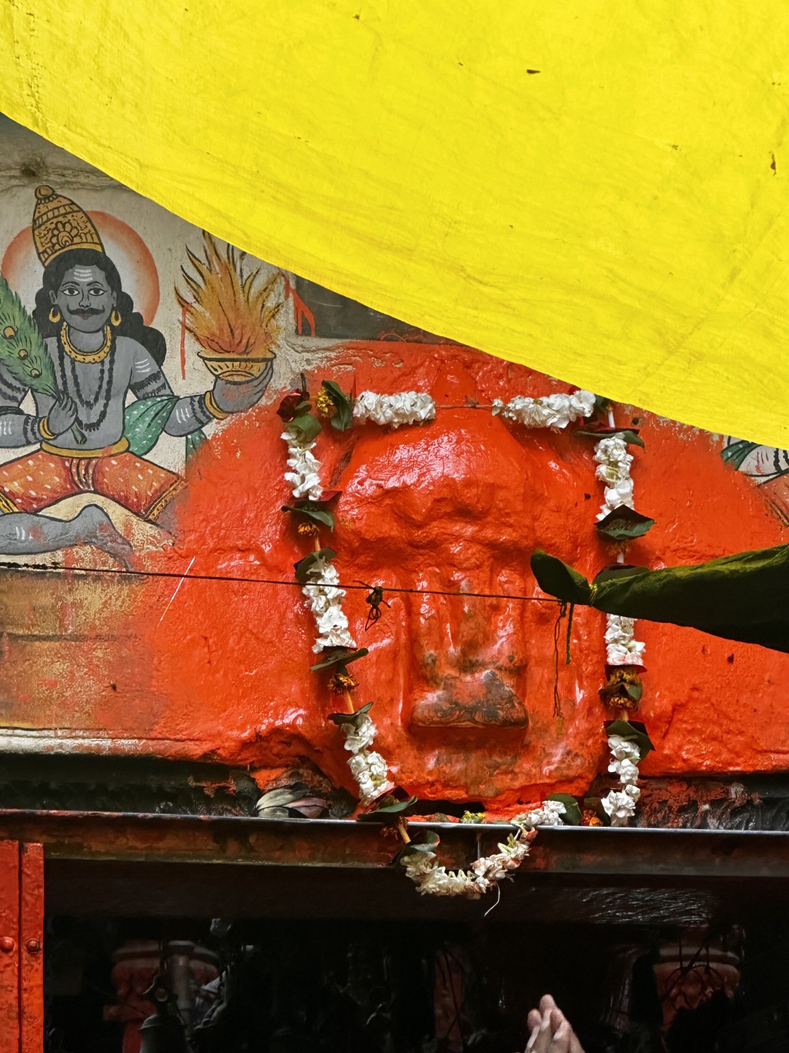 Vermilion-covered shrine decorated with a flower garland.