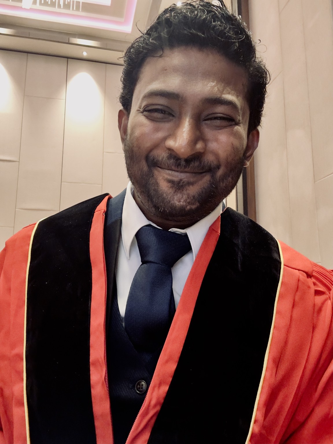 Thana smiling in his graduation gown