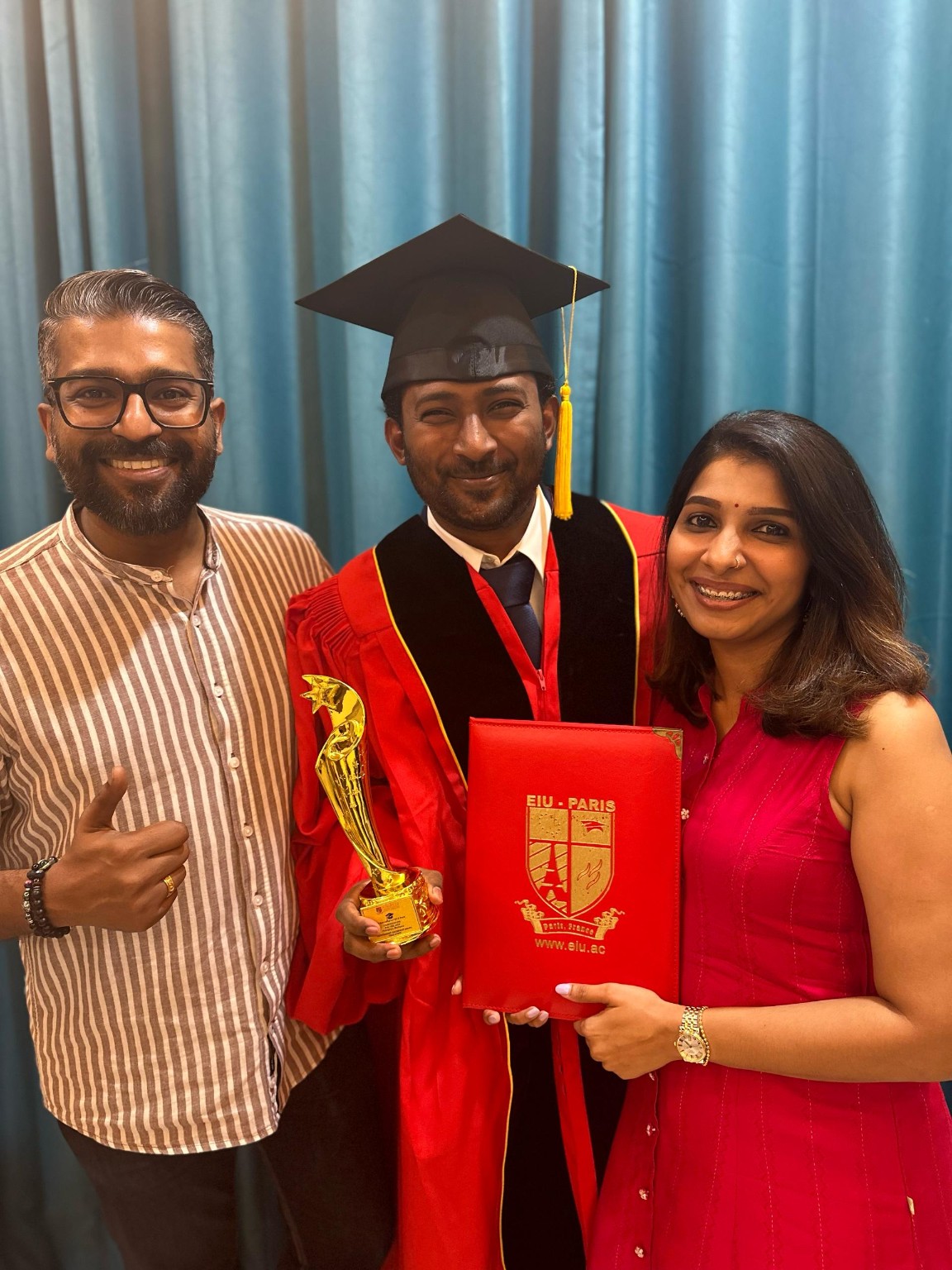 Thana holding his certificate and award with two guests