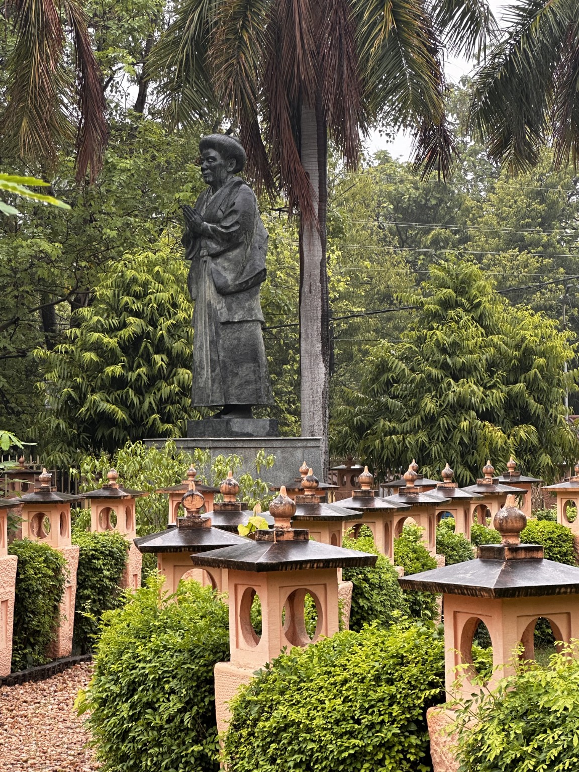 Temple garden with a standing figure and rows of small shrines