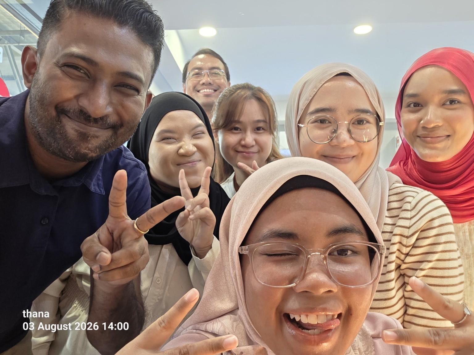 Thana smiling in a group selfie