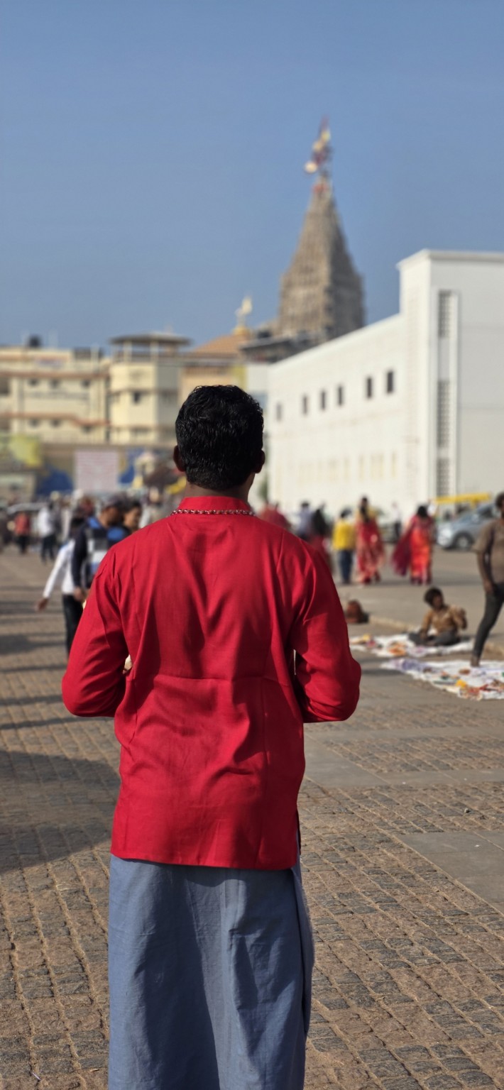 Thana in a red shirt walking towards Dwarkadhish Temple