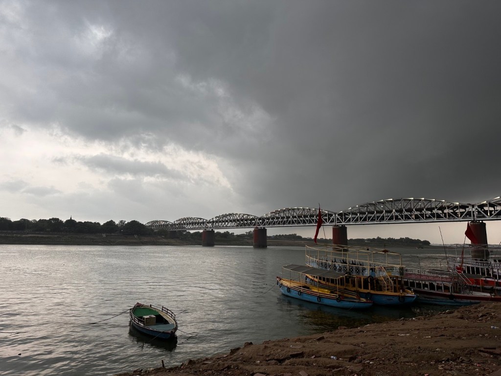 Boats on the Ganga beneath a cloudy sky.