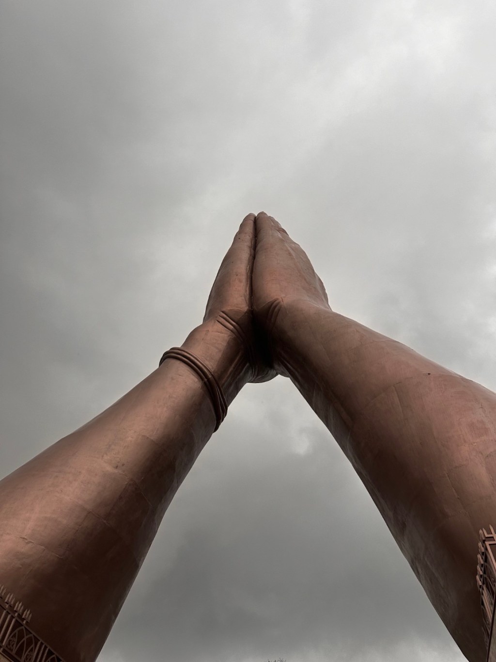 Hands joined in prayer against the sky.