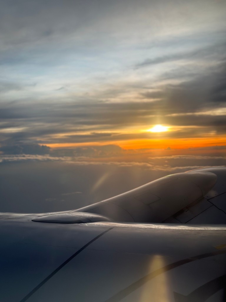 Sun seen through clouds above an aircraft wing