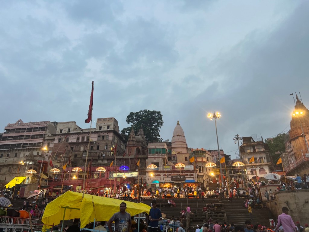 People gathered along the ghats as evening lights come on.