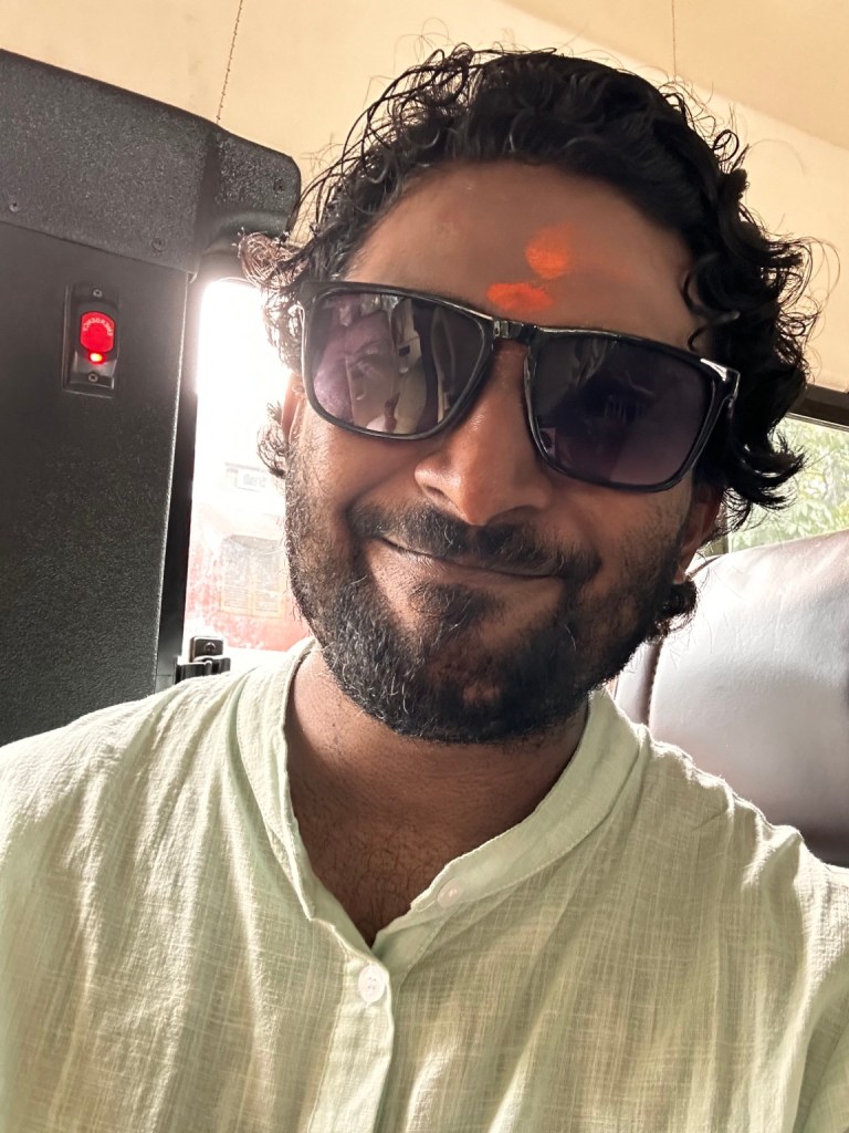 Thana wearing sunglasses and a light green shirt during the Kashi journey.
