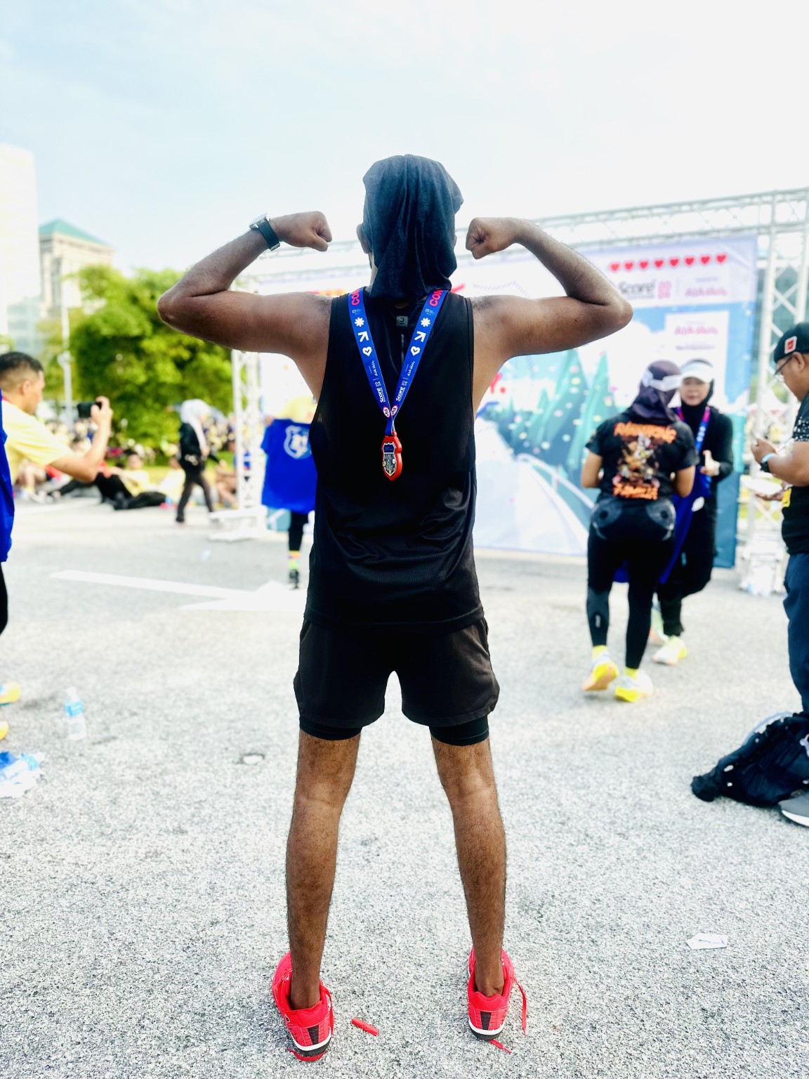 Thana celebrating his first half marathon with his medal hanging down his back.